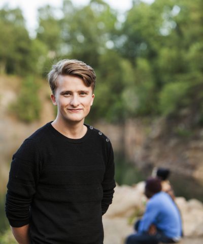 Portrait of smiling man standing at forest with friends in background